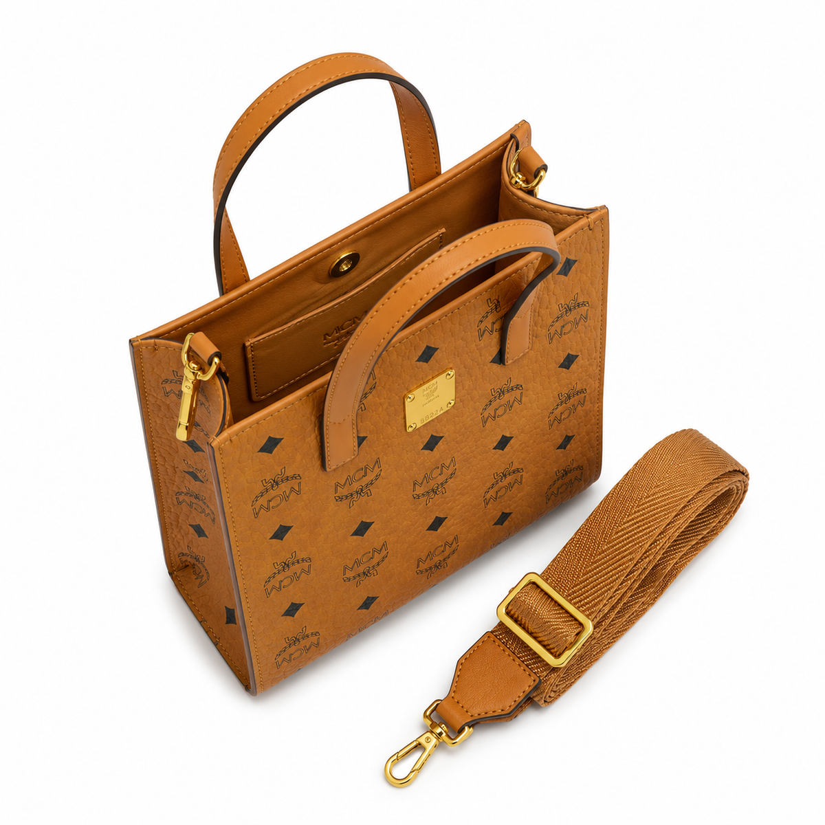 MCM cognac-colored full-width Monogram canvas with an adjustable webbing shoulder strap, suitable as a tote bag, shoulder bag, or crossbody bag.  Product Details