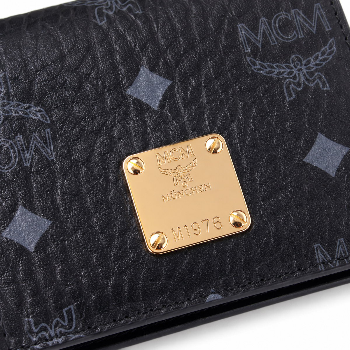 MCM women's clutch bag with all-over print in black and gold clasp featuring multiple card slots and zippered compartments
